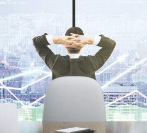 Businessman looks at the scoreboard with business chart and laptop with paper cup on wooden table